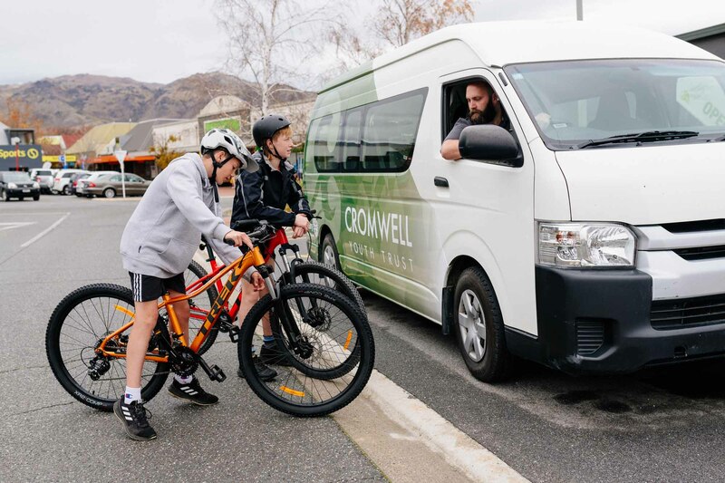 Kids on bikes beside youth trust van